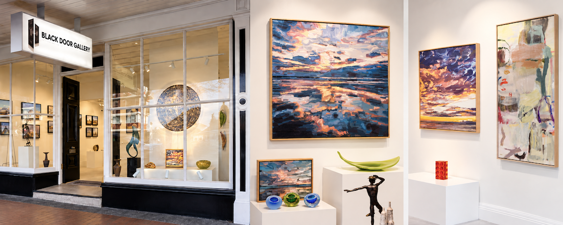 An art gallery interior with multiple framed paintings by artist Alex DiMercurio displayed on white walls, including a large square seascape painting, a vertical clouded sunrise scene, and a clouded abstract artwork. White display pedestals and a glass-front gallery entrance to Black Door Gallery are visible.