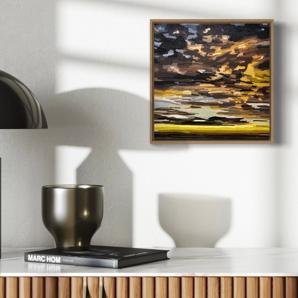 Abstract textural cloud painting with a mix of brown, black, and yellow colours. And some pale blue sky behind. Framed in wood.