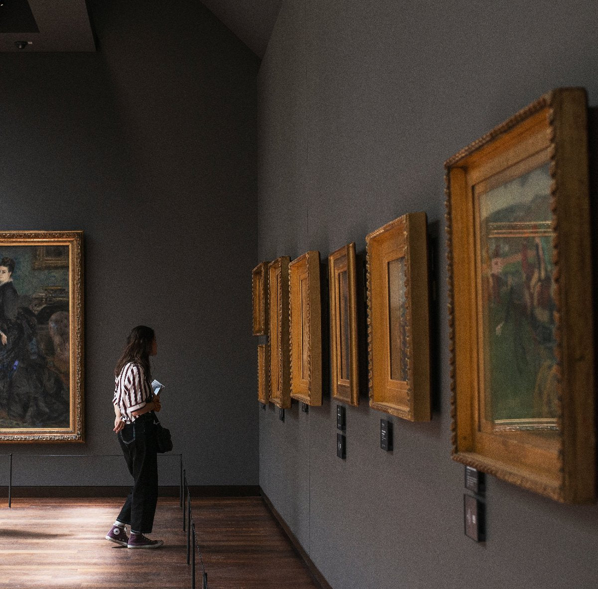 A woman standing in an art gallery admiring paintings